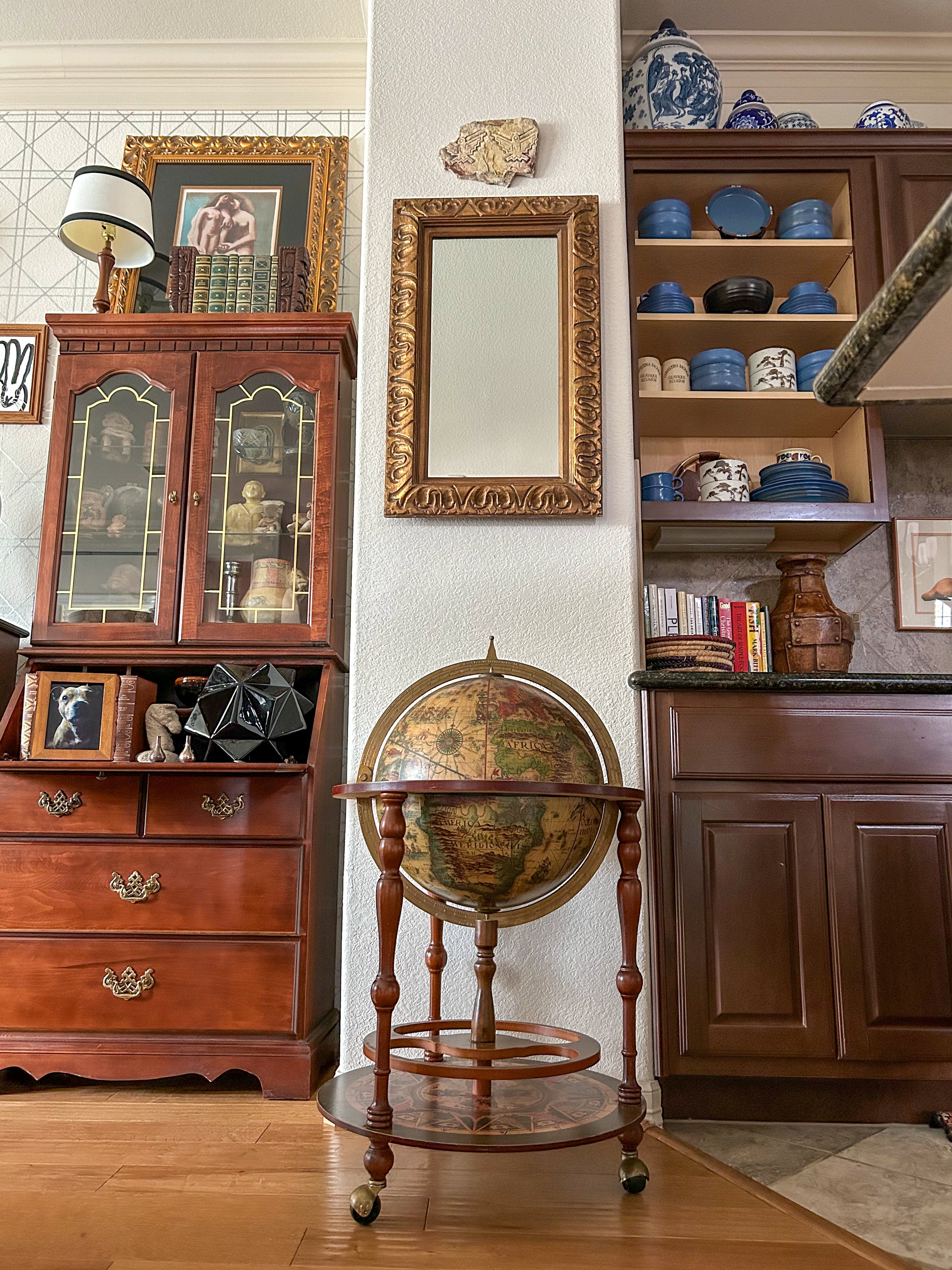 Sophisticated vignette by This Is Home Studio in Houston, Texas designed by Luke and Alejandra Fortin. Featuring vintage Italian globe, Hunt Slonem painting, vintage secretary desk, antique Scandinavian ceramic collection and a rare signed & numbered Picasso lithograph.